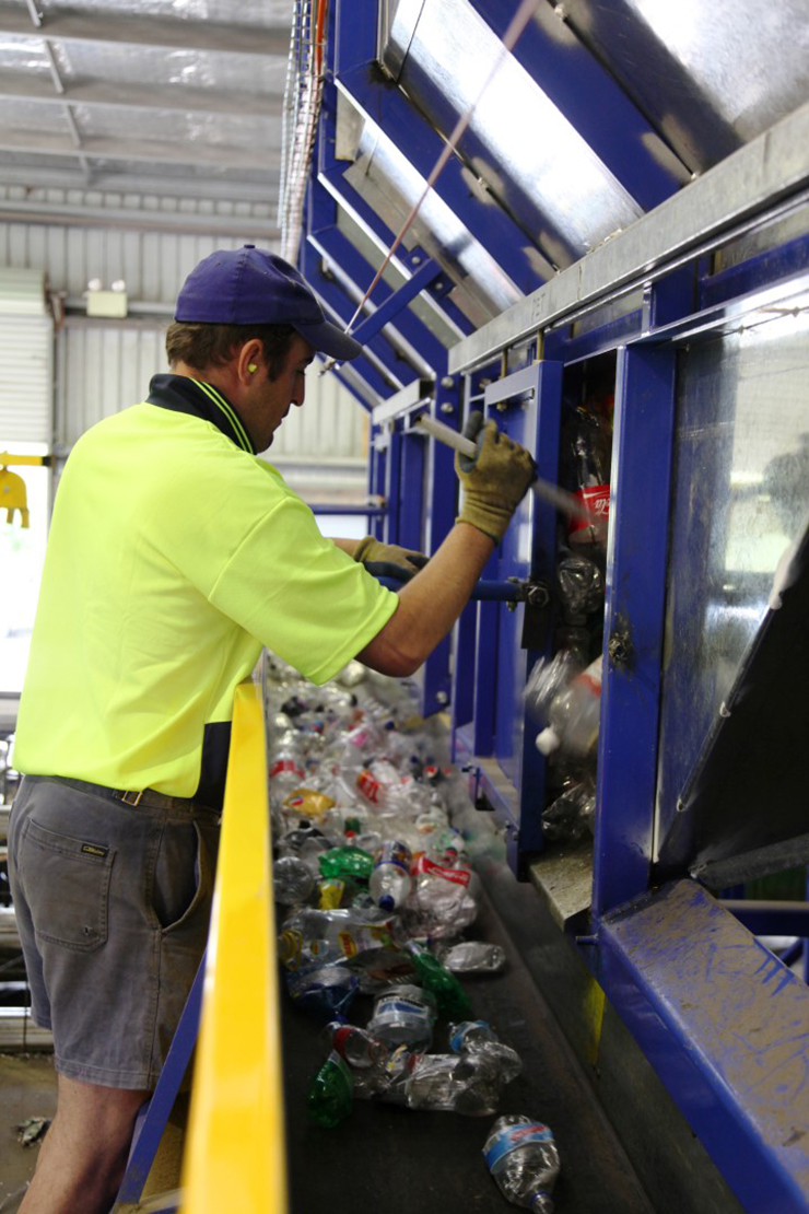Image of a staff member at the Challenge recycling plant, with plastic bottles to be recycled