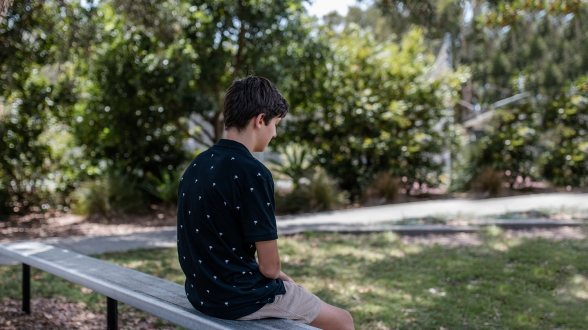 Image of 11 year old boy Robbie sitting on a park bench who is a current candiate for foster care with Challenge Community Services