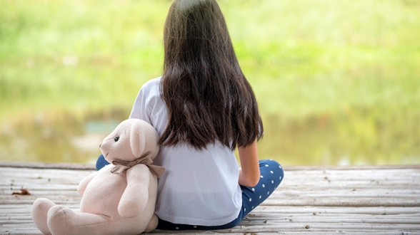 Image of 11 year old girl Lilly sitting with a stuffed toy bear who is a current candiate for foster care with Challenge Community Services